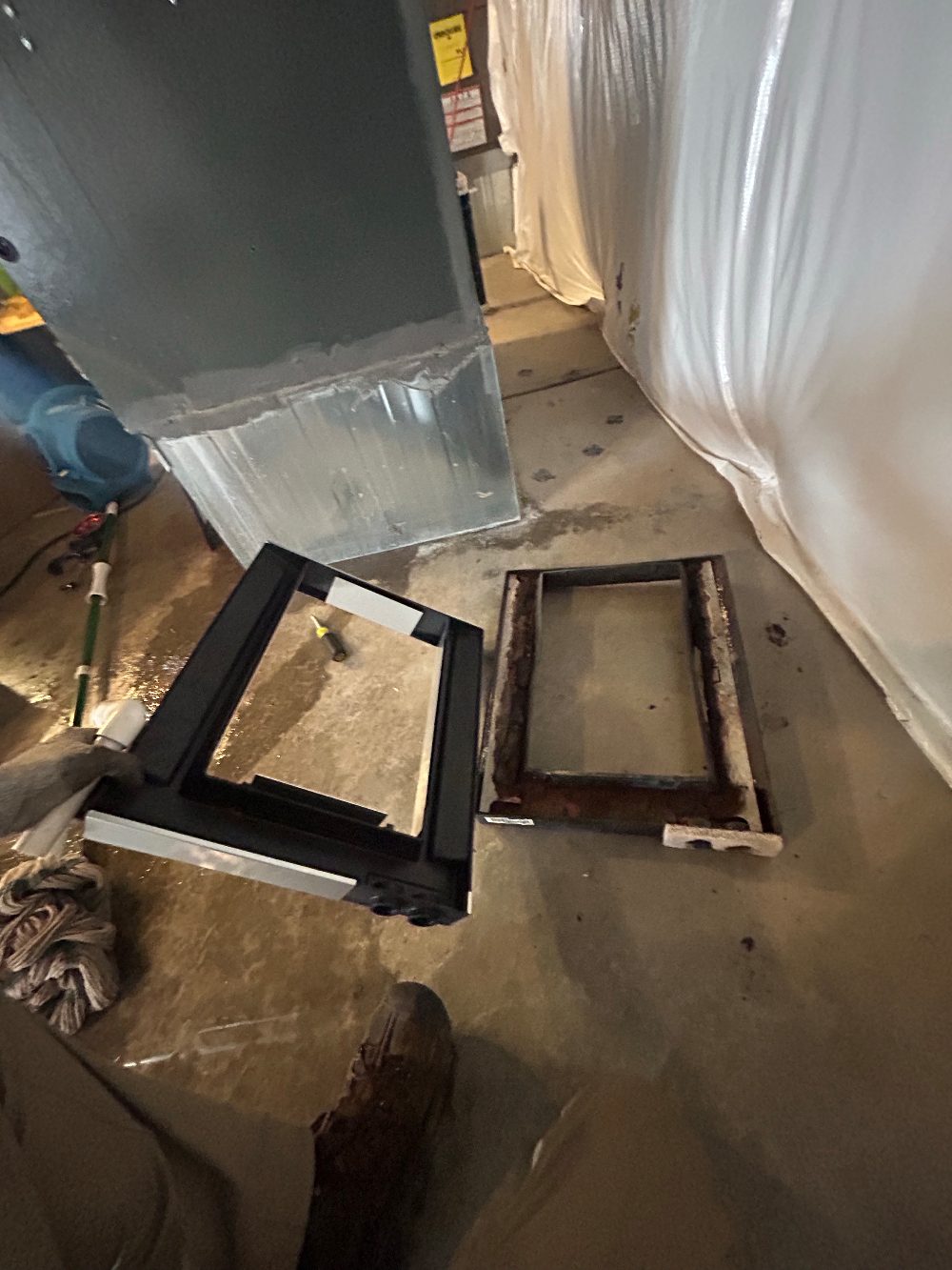 A rusted-through condensate drain pan next to its new replacement