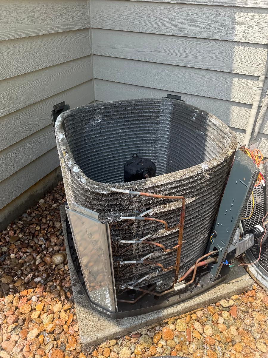 An outdoor AC condenser with its casing removed exposing the coil
