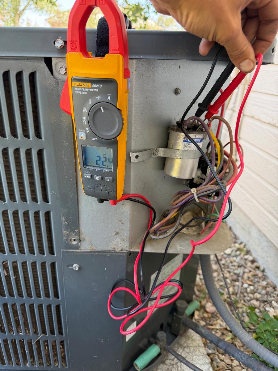Technician metering the electrical components of an outdoor AC unit