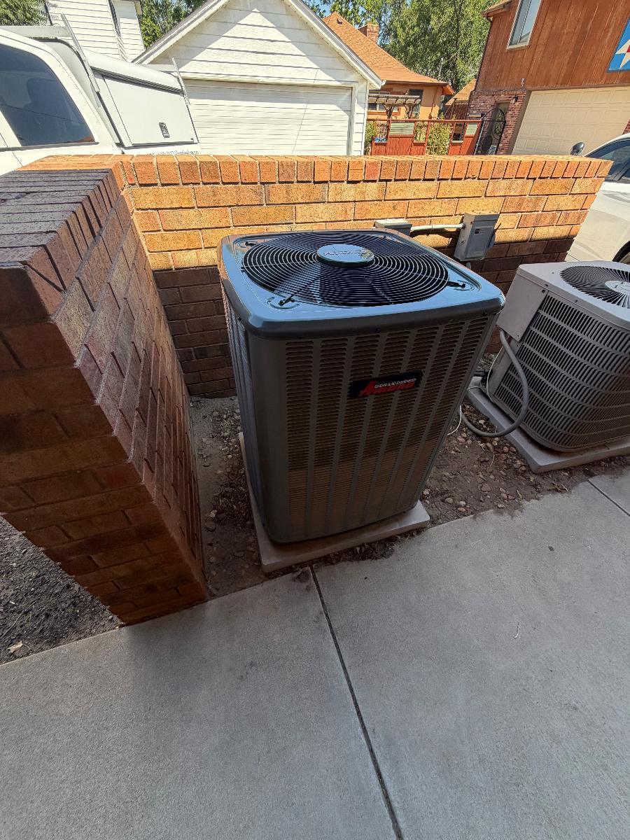 Two outdoor AC condensers installed side by side at a home