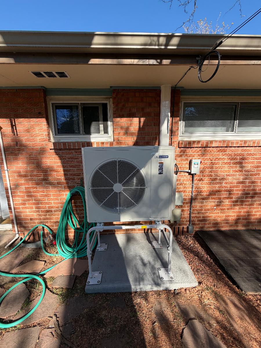 An outdoor ductless mini-split condenser mounted on a brick house wall