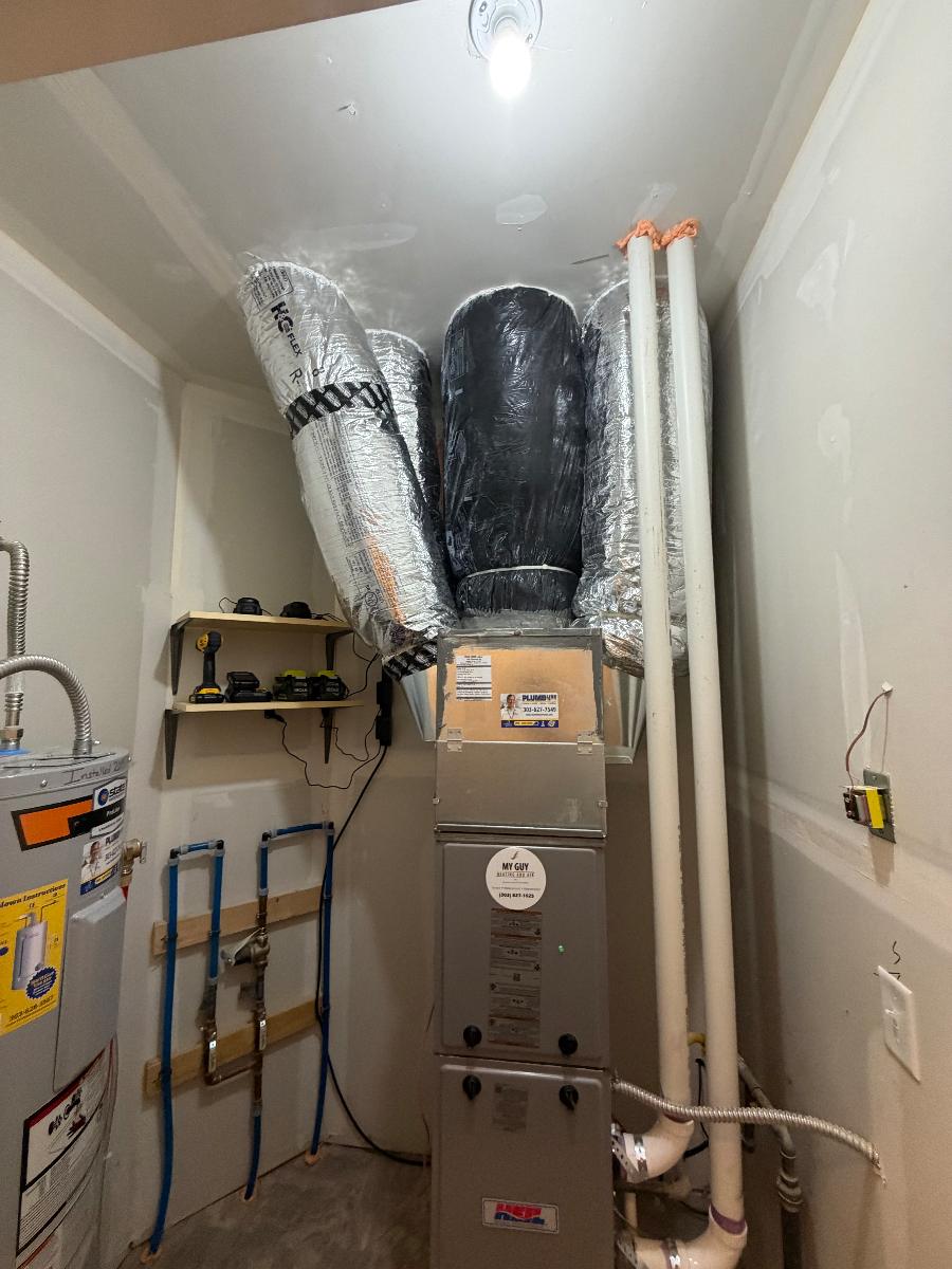A furnace and water heater installed in a clean utility closet with flex duct
