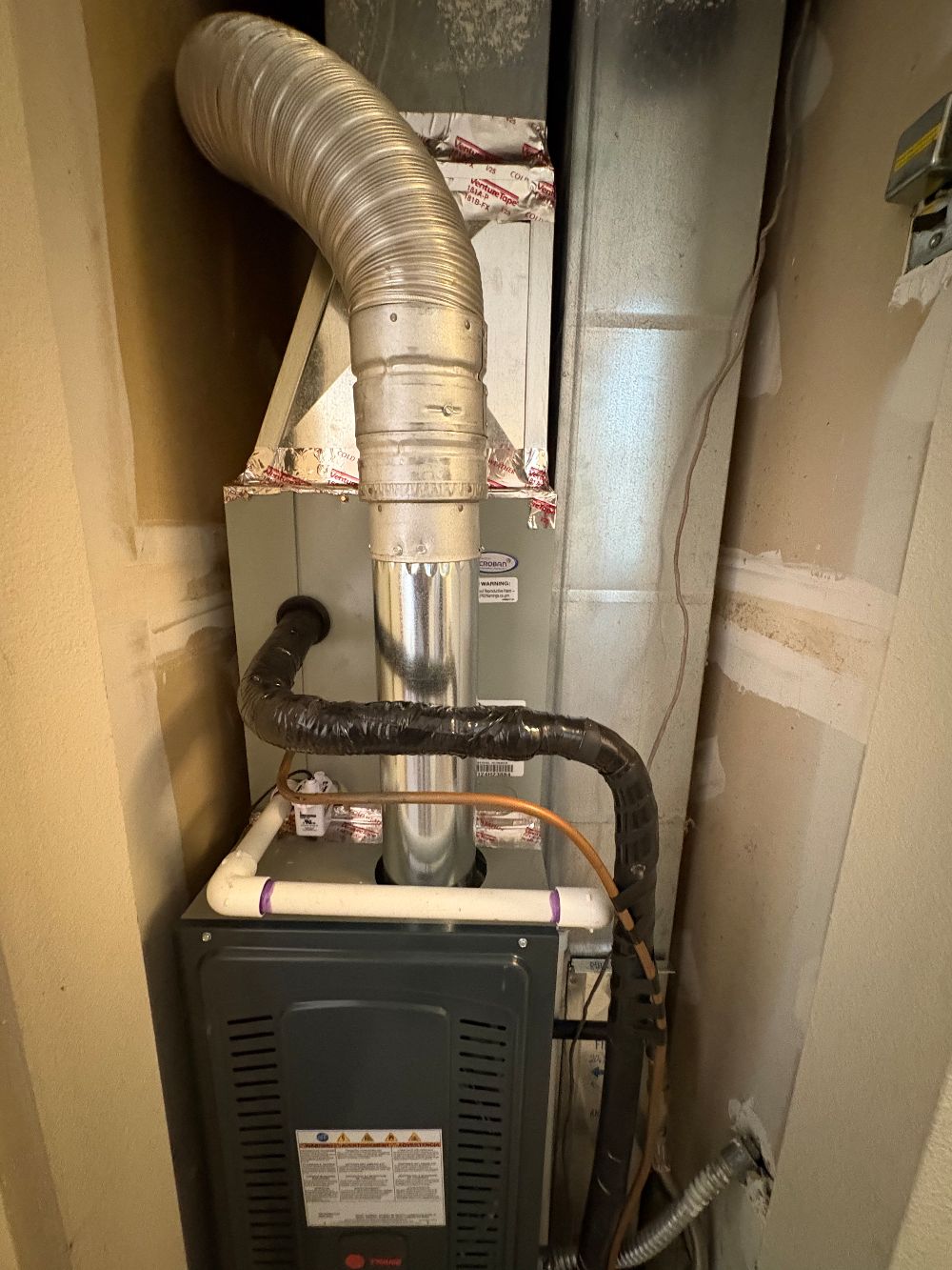 A clean gas furnace installation with tidy flue venting and refrigerant line set