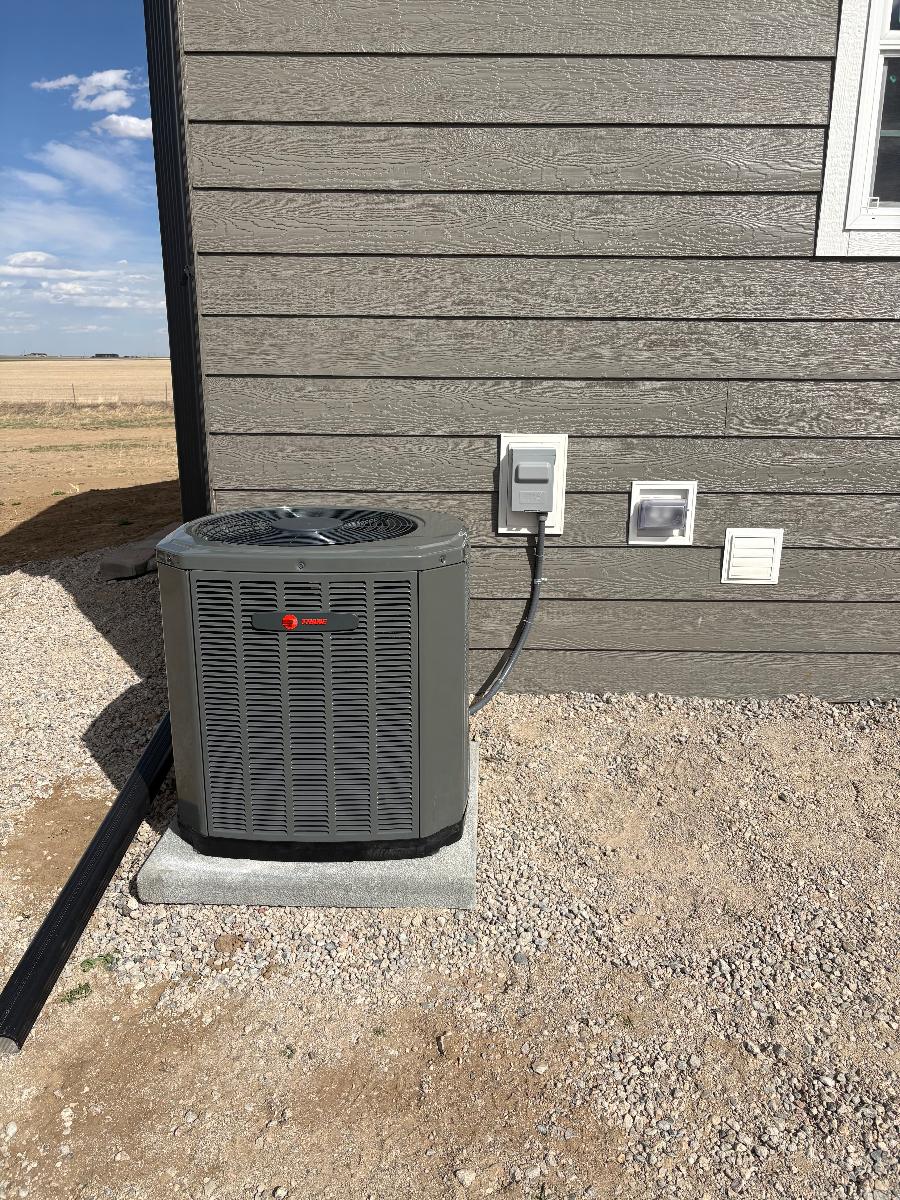 A newly installed outdoor AC condenser beside a home