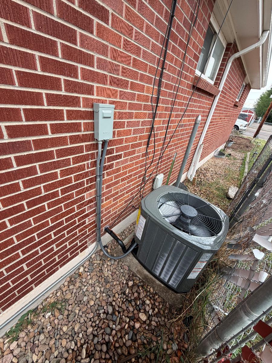 A new outdoor AC condenser installed beside a brick house